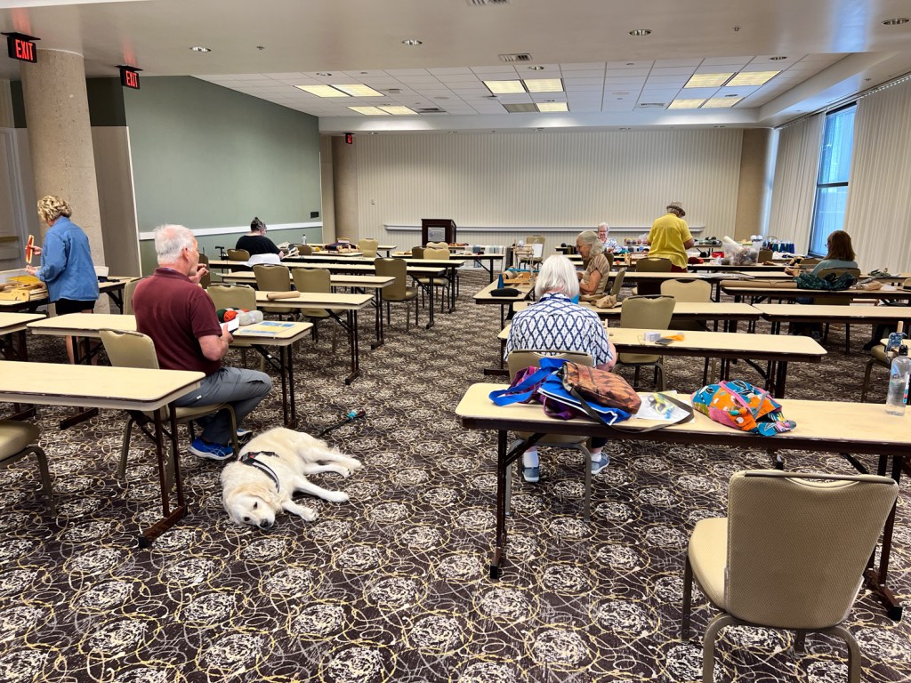 Room with several tables and weavers at their looms. 