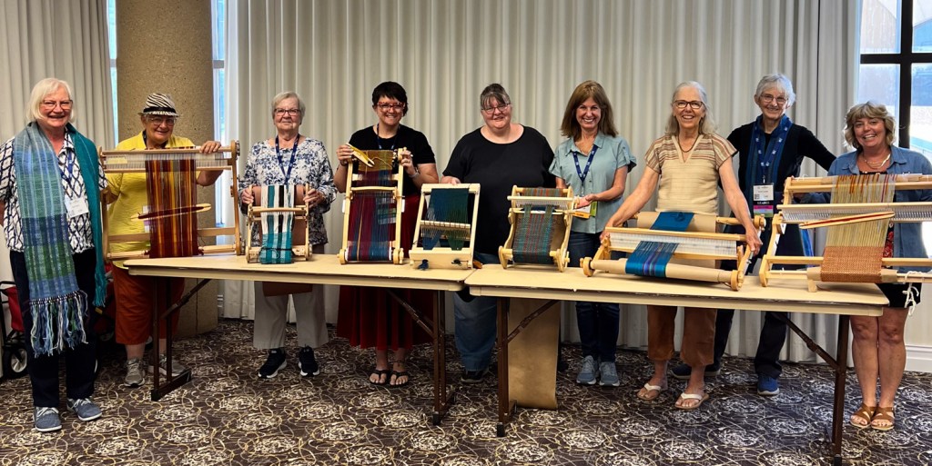 People in a weaving class holding their looms with projects in progress.