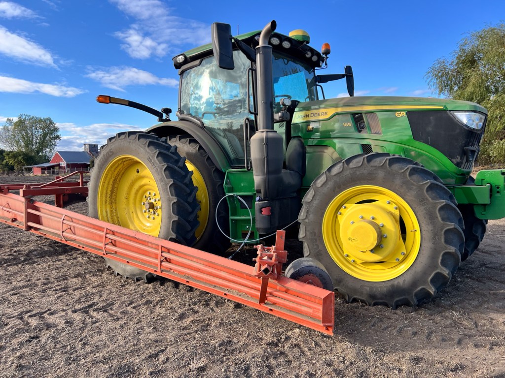 Green and yellow tractor with orange border maker attached.