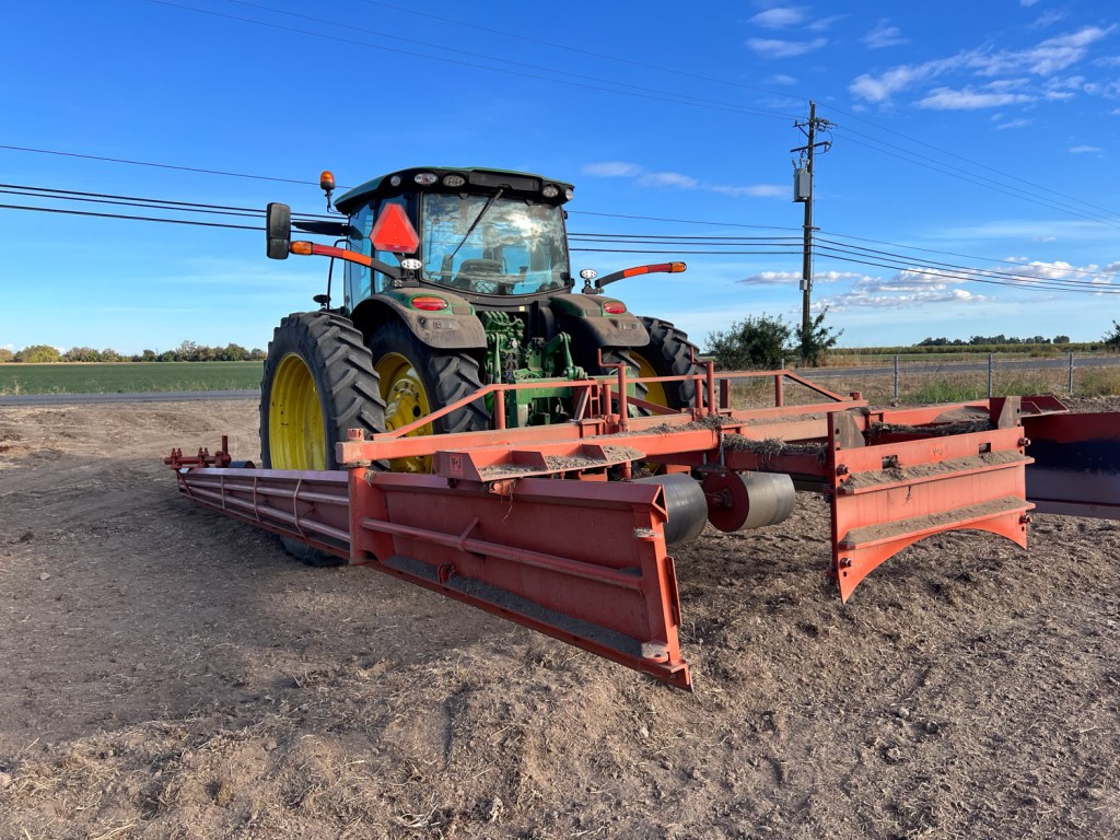 Green tractor with orange border maker attached. 