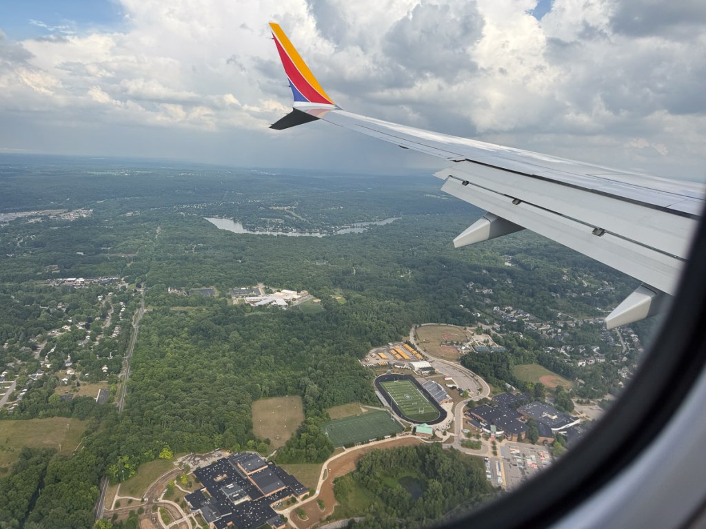 View for the forest and city from the window a Southwest airplane, including a view of the wing tip.