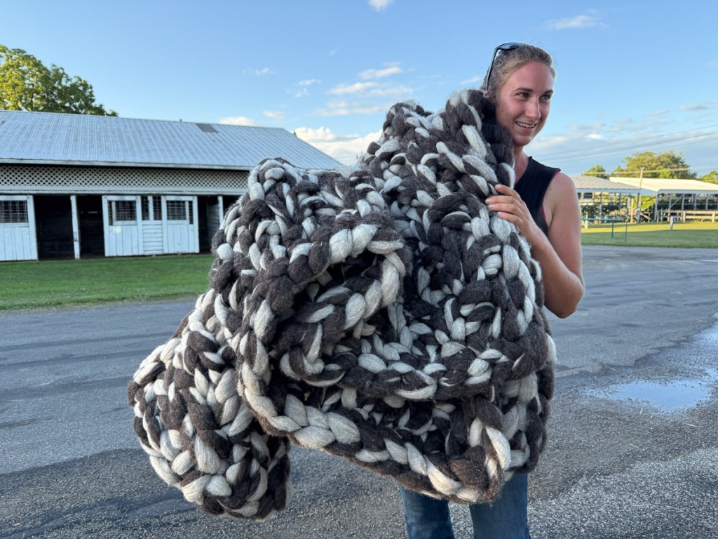 Woman with large blanket knitted with gray and white roving.