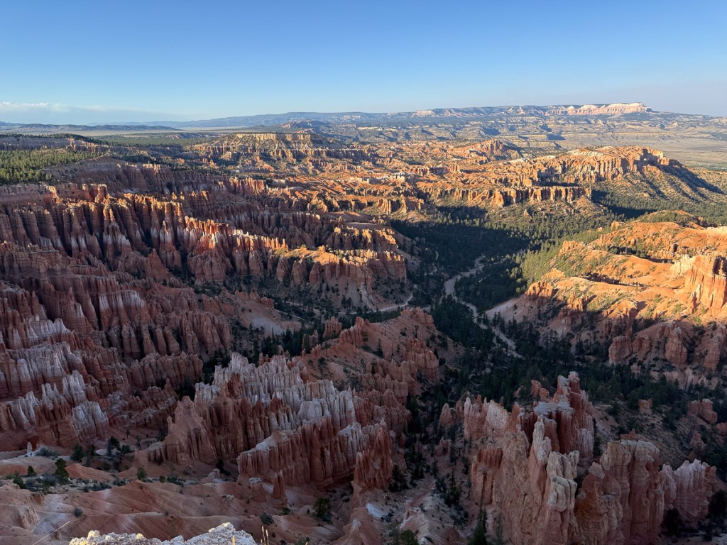 Looking over  Bryce Canyon National Park seeing canyons below and cliffs in the distance.
