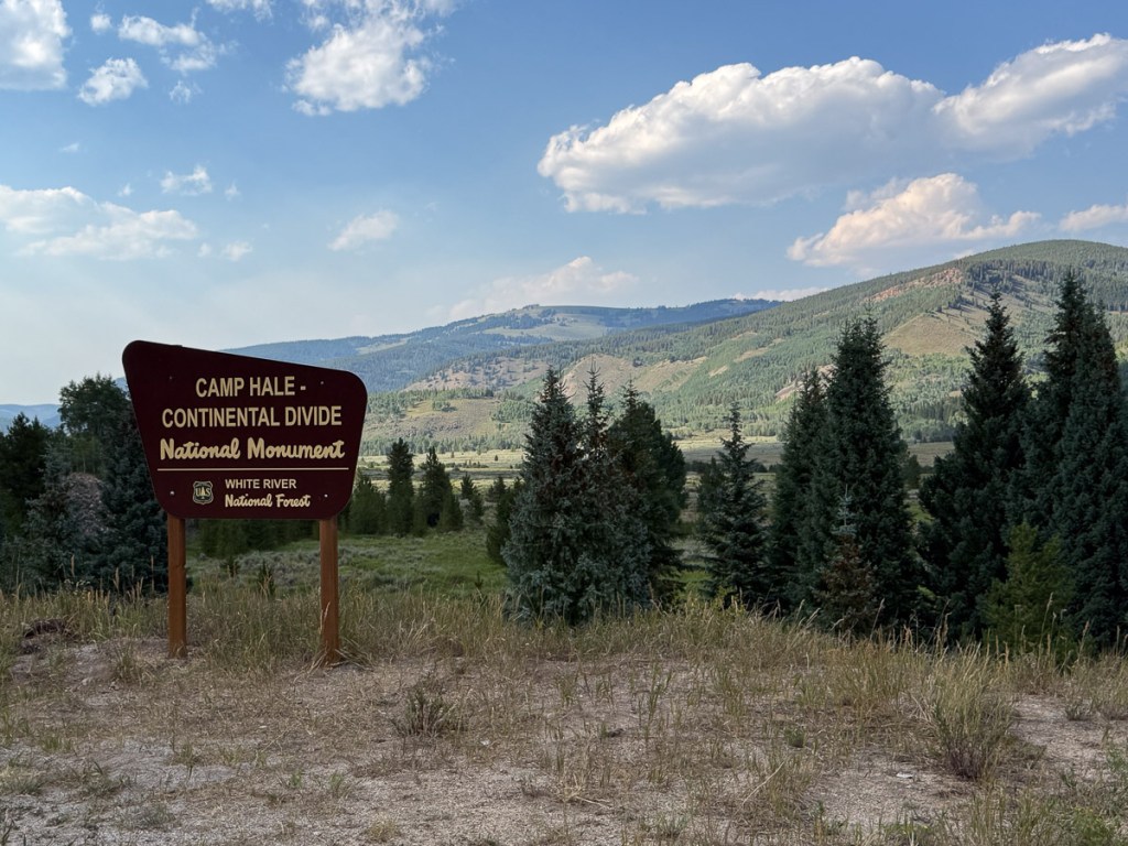 Sign for Camp Hale National Monument on the Continental Divide. Mountains and trees in the background.