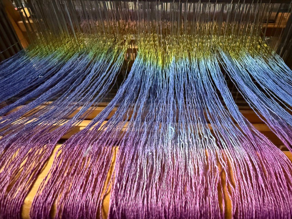 Space-dyed pink, blue, and yellow yarn  on loom. 