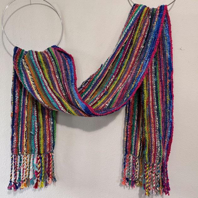 Colorful striped scarf draped though rings on the wall.