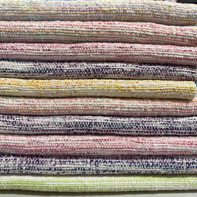 Stack of ten colorful baby blankets in pinks, purple, and yellow.