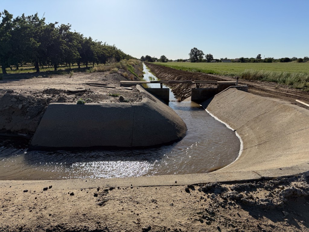Cement-lined irrigation canal with water.