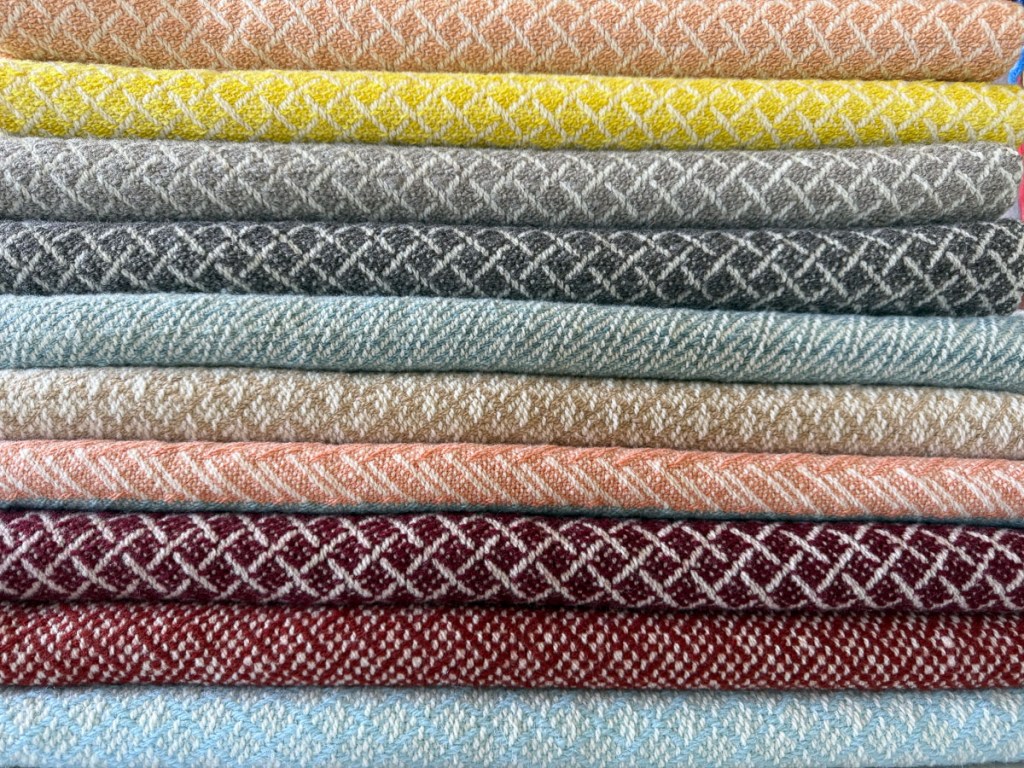 Stack of handwoven wool blankets with a variety of colors and patterns.