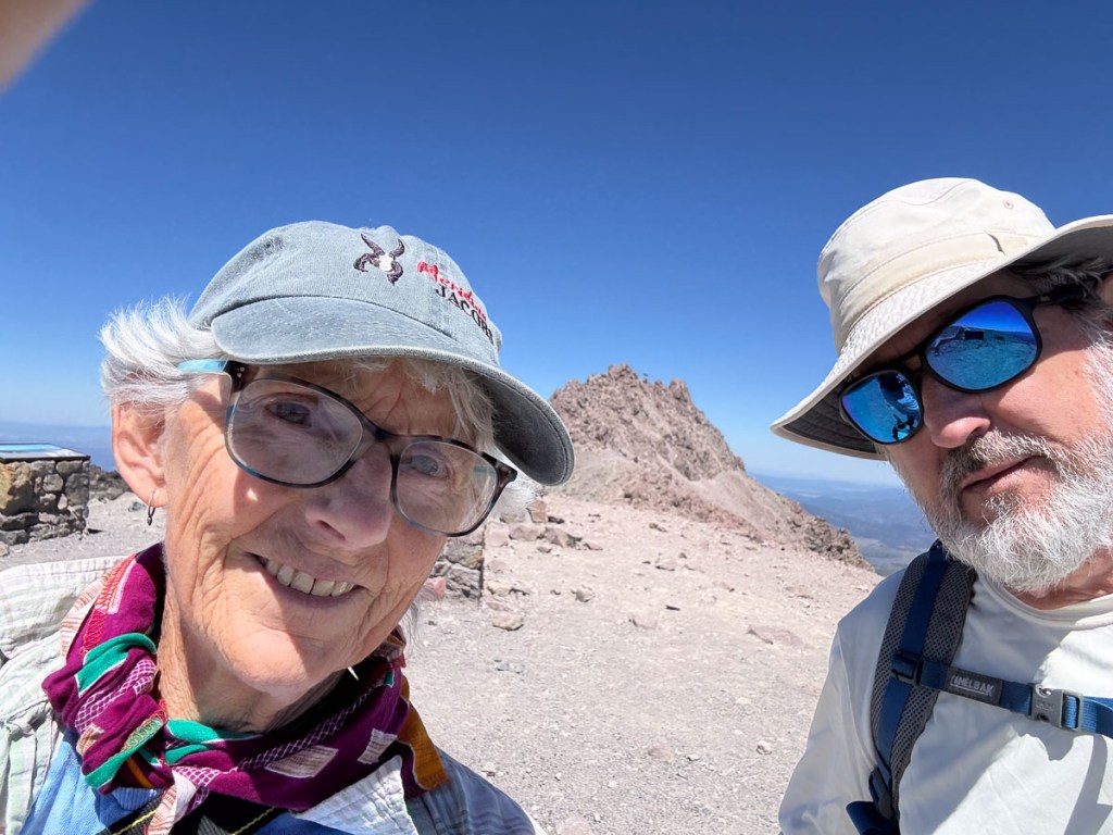 Robin and Dan in a selfie with Lassen Peak and blue sky in the background.