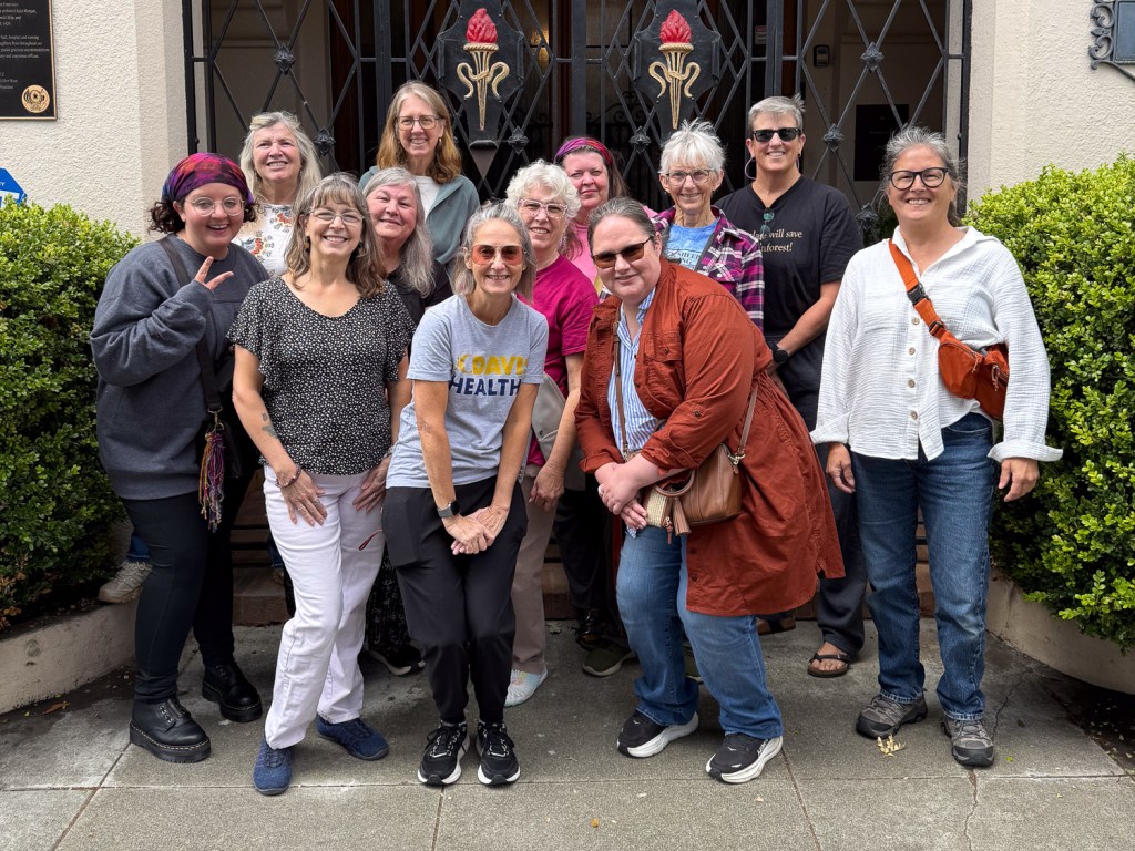 Group photo of twelve women outside gated entrance.